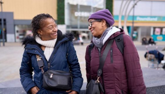 two women chatting happily in a shopping street