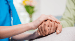 Healthcare worker holding a patient's hand