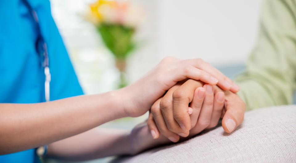 Healthcare worker holding a patient's hand