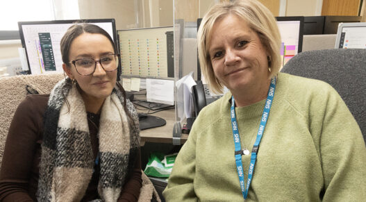two women sitting next to each other in an office