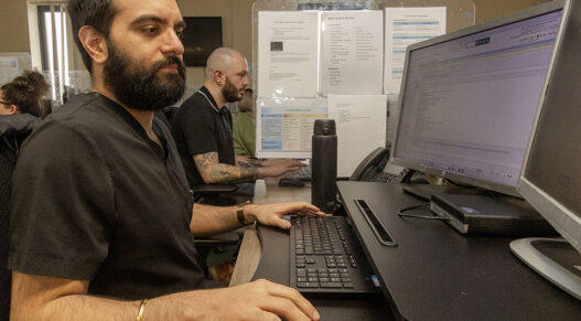 A man sitting at a computer with another man next to him