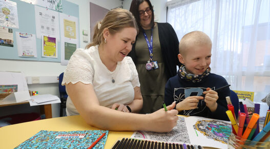 a child right plays with pens, with her mother and another woman looking on