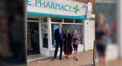three people standing in front of a pharmacy