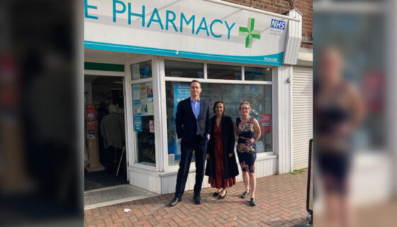 three people standing in front of a pharmacy