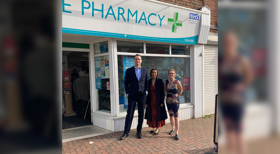 three people standing in front of a pharmacy